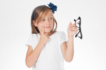 child- girl with glasses - in a white t-shirt - holding glasses.