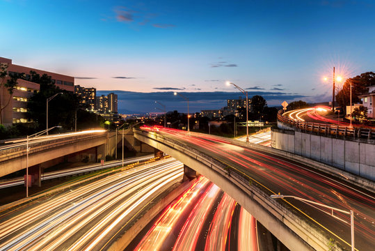 Light trails over H1 highway in downtown Honolulu, Hawaii during sunset golden hour