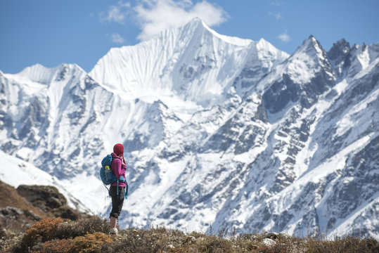 A woman trekking in the Langtang Valley with a view of Ganchempo in the distance, Langtang Region, Himalayas, Nepal