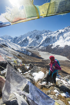 A woman trekking in the Langtang valley in Nepal stands on the top of Kyanjin Ri and looks out towards Ganchempo in the distance, Langtang Region, Nepal
