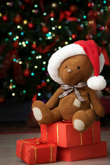 Christmas gifts and Teddy bear in Santa hat on a background of garlands