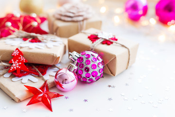 Christmas and New Year background with magenta purple decorative ball, presents and decorations for Christmas tree. Holiday background with stars confetti and light bulbs. Place for text.