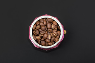 Italian moka pot full of roasted coffee beans. Top view isolated