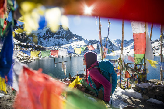 A trekker stands among prayer flags beside the holy lakes at Gosainkund in the Langtang region, Himalayas, Nepal