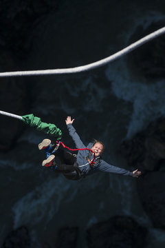 A woman smiles for the camera as she is bounced back up during a Bungee jump at The Last Resort, Nepal