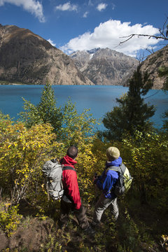 Trekkers look out at the turquoise blue Phoksundo lake, Dolpa Region, Nepal