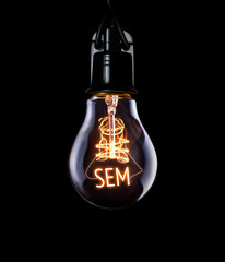 Hanging lightbulb with glowing SEM concept. - obrazy, fototapety, plakaty