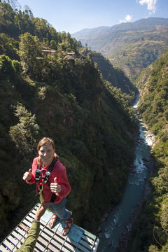 Standing on then edge, a girl prepares herself to take a bungy jump backwards, Nepal