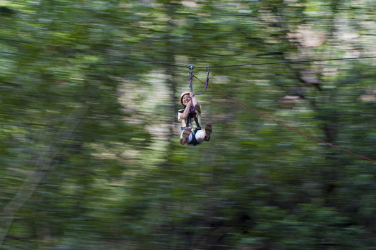 A girl clings on and laughs with delight on a zip line, Nepal