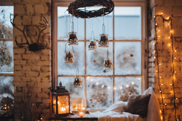 Christmas decorations hang on the background of candles, windows and garlands