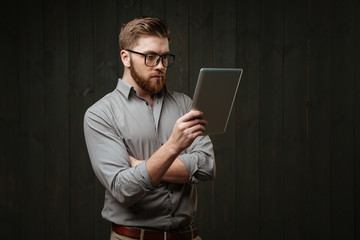 Man in eyeglasses looking at tablet computer in his hand