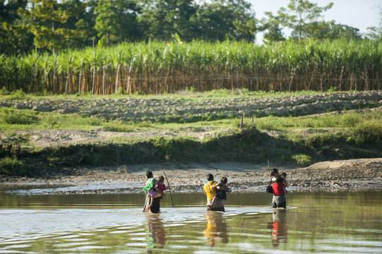Women cross a river carrying their children in their arms, Chittagong Hill Tracts, Bangladesh