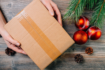 A girl holding a box over the table. Parcel delivery. Christmas background.