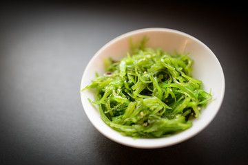 Wakame salad or seaweed salad on dark background. Selective focus.