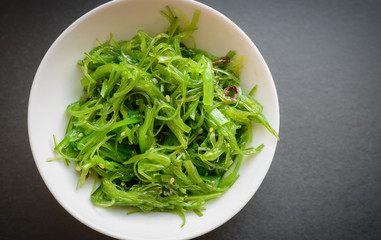 Wakame salad or seaweed salad on dark background. Selective focus.