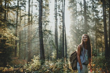 Hipster girl tourist with backpack is traveling in the woods