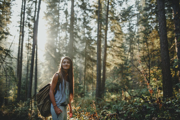 Hipster girl tourist with backpack is traveling in the woods