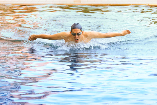 dynamic and swimmer in cap breathing performing the butterfly st
