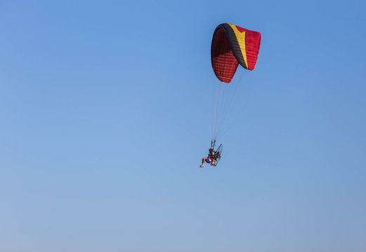 paraglider flying with paramotor on  blue sky  background