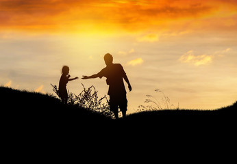 Fototapeta na wymiar Silhouette father stretch hand helping to daughter on sunset