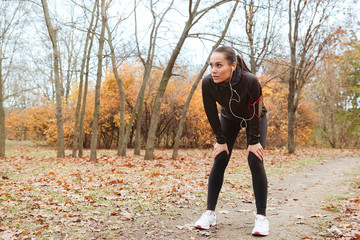 Fototapeta premium Young woman runner in warm clothes running in autumn park