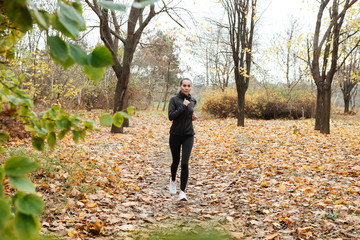 Young woman runner in warm clothes and earphones