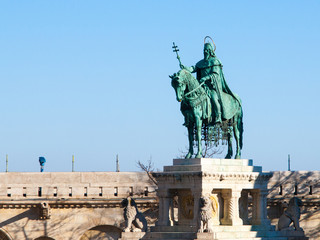 Fototapeta premium Mounted statue of Saint Stephen I, aka Szent Istvan kiraly - the first king of Hungary at typical white rounded tower of Fisherman's Bastion in Buda Castle in Budapest, Hungary, Europe. Sunny day shot
