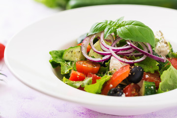 Greek salad with fresh tomato, cucumber, red onion, basil, lettuce, feta cheese, black olives and Italian herbs