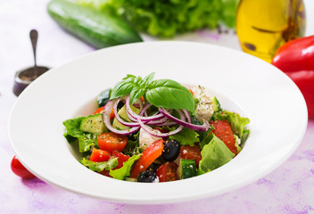 Greek salad with fresh tomato, cucumber, red onion, basil, lettuce, feta cheese, black olives and Italian herbs