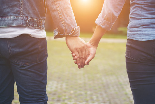 Close-up of loving couple holding hands while walking outdoor, C