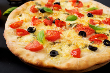 Pizza with tomato, mozzarella, basil and olives.