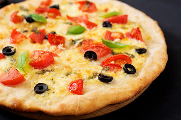 Pizza with tomato, mozzarella, basil and olives.