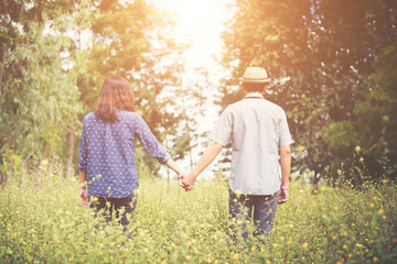 Fototapeta premium Rear view of young hipster woman walking with her boyfriend on g