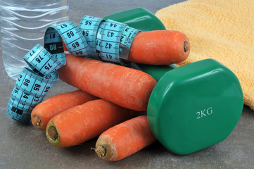 Haltère avec des carottes, un centimètre de couturière et une bouteille d'eau