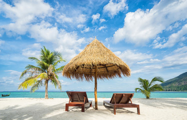 Vakantie in tropische landen. Strandstoelen, parasol en palmen op het strand.