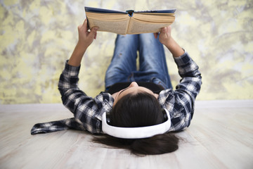 teen girl in headset reading a book