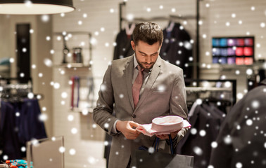 happy young man choosing shirt in clothing store