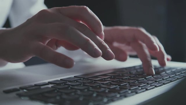 Close up of female hands typing on keyboard in the evening light. Typing work on computer. Typing text and using touch pad on a laptop computer keyboard. Woman hands in white blouse