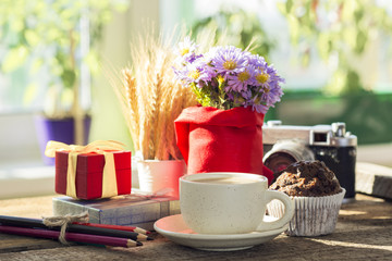 sunny morning breakfast table with a cup of coffee, bouquet of blue flowers muffins and old camera....