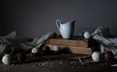 still life, vintage. candy, drapery, milk, book, letter on the wooden table. black background