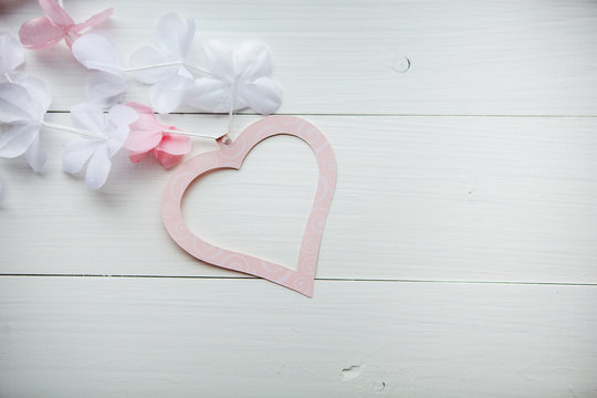 нежное розовое сердце из бумаги с белыми и розовыми цветами на белом деревянном столе ко дню святого валентина