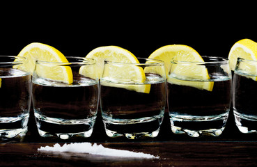Tequila shots with lemons and salt on the wooden table. Selective focus and small depth of field.