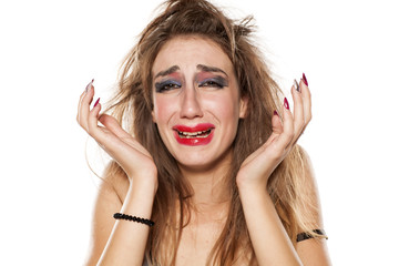 crying young woman with bad makeup and messy hair