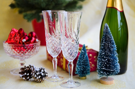 Bottle of champagne, two  elegant flutes, mini fir trees,  christmas tree decoration and gift box. Xmas or  New Year concept in red gold tone