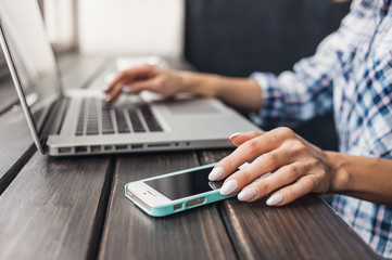 Young beautiful woman sitting at a cafe and using smartphone and laptop computer