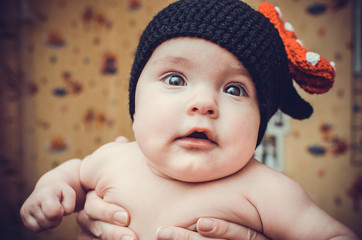 Little cute girl in black knitted hat looks at the world with th