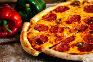 Whole pizza with sausages and pepper on wood table with ingredients