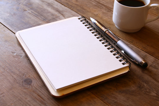 open notebook with blank pages next to cup of coffee