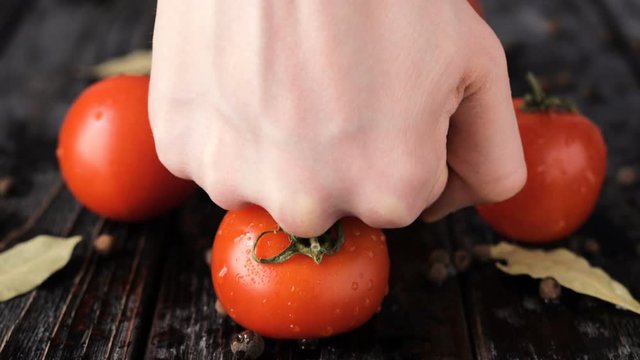 smashing of little ted tomatoes by fist on dark wooden table
