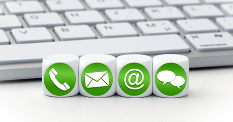 Contact us page concept with green and white icons on cubes in front of a keyboard
